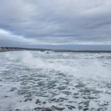 Shallow water pulling back from a shoreline as the tide ebbs.