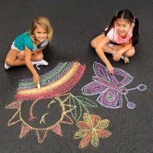Children making colorful chalk drawings on a sidewalk.