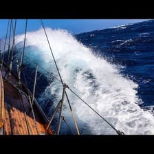 A sailboat being repeatedly battered by rough ocean waves