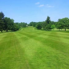 Open mown fairway stretching from a golf tee toward the green