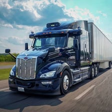 Several large semi-trucks traveling on a highway.
