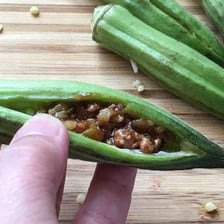 Fresh green okra pods beside a bowl of gumbo.