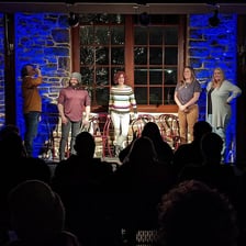 Comedians performing improvisational comedy on a club stage.