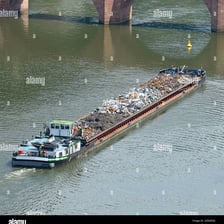 A flat-bottomed barge carrying refuse on a river