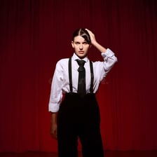 A stylish performer displaying energetic confidence on stage.