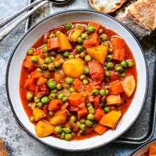 Green peas visible in a bowl of vegetable stew