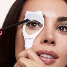 Mascara being applied to eyelashes with a cosmetic brush.