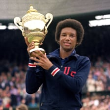 Arthur Ashe playing tennis in competition.