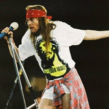 Axl Rose performing with a microphone on stage