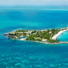A small, low tropical island surrounded by clear water