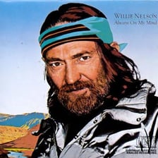 Willie Nelson performing onstage with a guitar.