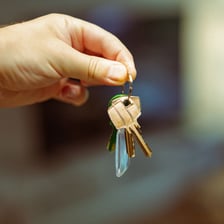 A person holding keys to indicate ownership of a property.