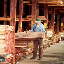 A worker cutting wooden boards with a saw