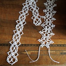 A person making lace by tatting thread with a shuttle