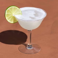 A vodka gimlet cocktail garnished with lime