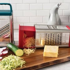 A piece of food being grated on a metal box grater