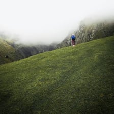 A solitary hiker standing in a broad landscape.