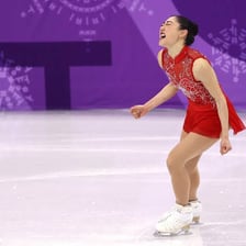 A figure skater airborne during an axel jump