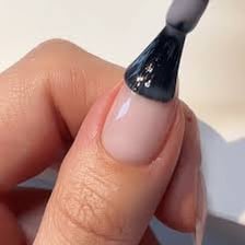 A close-up of nail polish being applied as a layer to a fingernail.