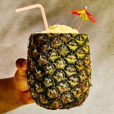 A piña colada cocktail garnished with pineapple.