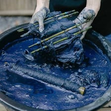 Fabric being immersed in blue dye and taking on a blue color.
