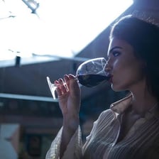A person taking a small sip of wine