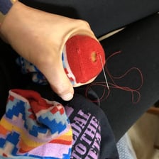 A person sewing a repair into a sock.