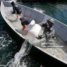 A person removing water from a boat with a bucket