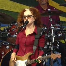 Bonnie Raitt performing with a guitar on stage