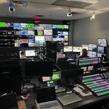 A television broadcast control room with monitors and production equipment.