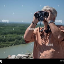 A person observing a distant landscape through binoculars.