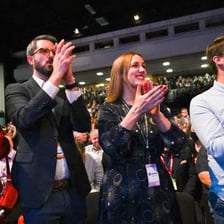 A speaker praising a person before an applauding audience.