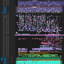 A film editor working with short movie clips on an editing timeline.