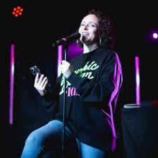 A poet performing at a poetry slam on a small stage.