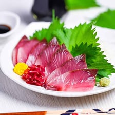Slices of yellowtail sashimi beside a whole yellowtail fish.