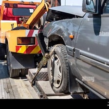 A tow truck pulling a disabled car on a road