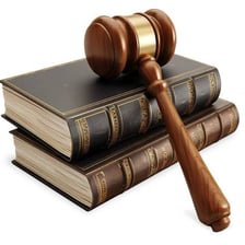 Law books and a judge’s gavel beside a courthouse
