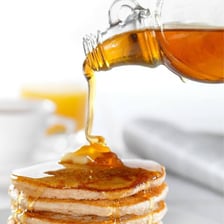 Thick maple syrup being poured from a container.