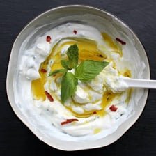 A bowl of thick labneh garnished with olive oil and herbs.