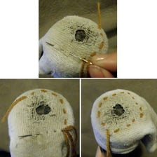 A hand repairing a hole in a sock with needle and thread.