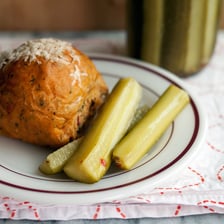 A deli sandwich served with a sour pickle spear.