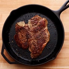 A steak being seared in a hot skillet