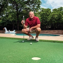 A golfer using a putter on a golf green.