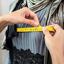 A tailor modifying a garment with a measuring tape.