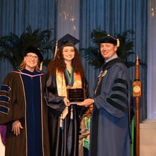 Graduates holding diplomas at a commencement ceremony.