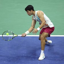 A tennis player playing a soft shot close to the net.
