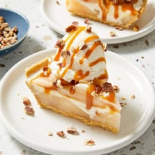 A slice of apple pie topped with a scoop of vanilla ice cream
