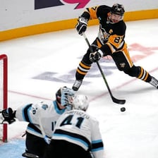 An ice hockey player shooting the puck into the net.
