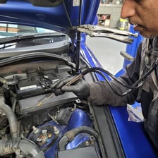 A mechanic inspecting a car engine for an unusual metallic sound.