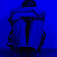 A person sitting alone with a visibly melancholy expression.